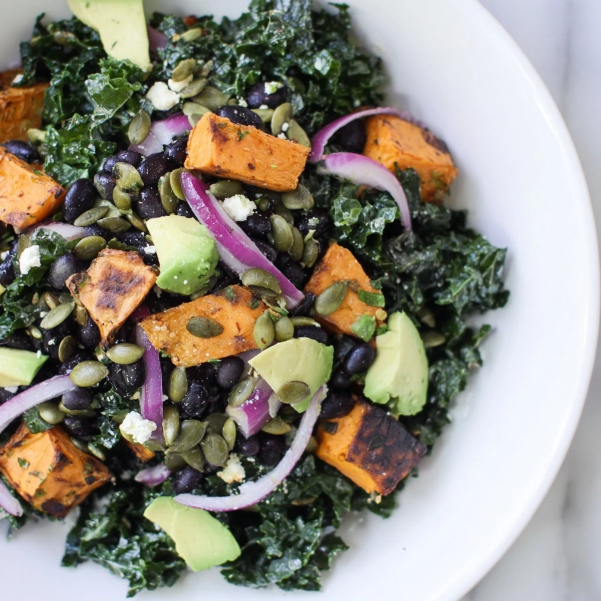 Bright, colorful photo of the delicious Massaged Kale Salad with black beans and roasted sweet potatoes.