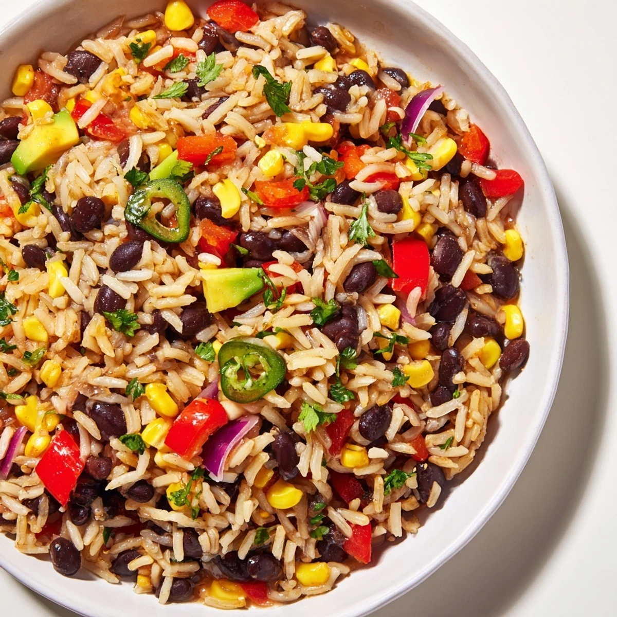 Close-up of a warm bowl of One-Pot Mexican Rice & Beans, garnished with fresh cilantro and lime.
