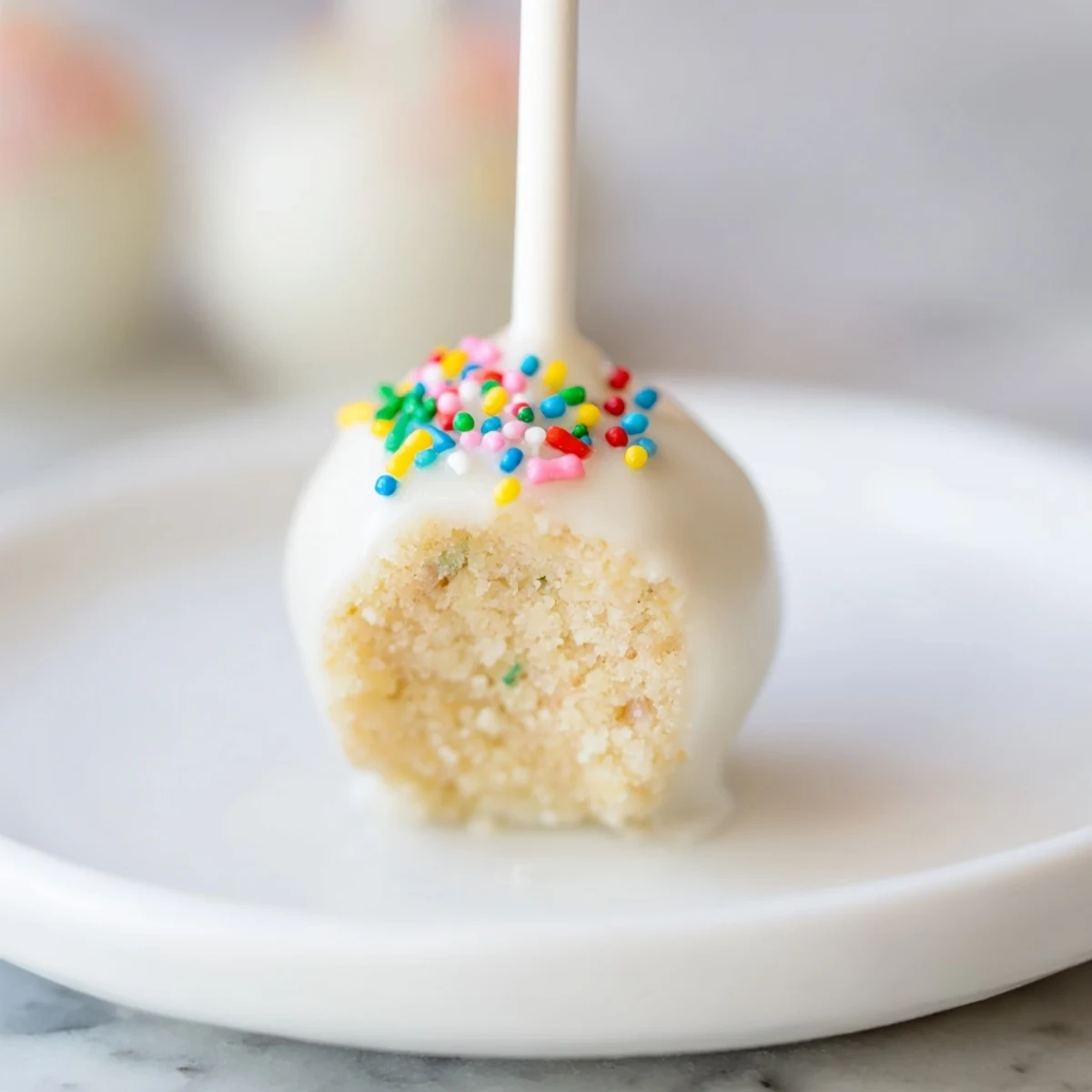 These Lightened-Up Sugar Cookie Cake Pops are coated in white chocolate with colorful sprinkles, a perfect indulgence.
