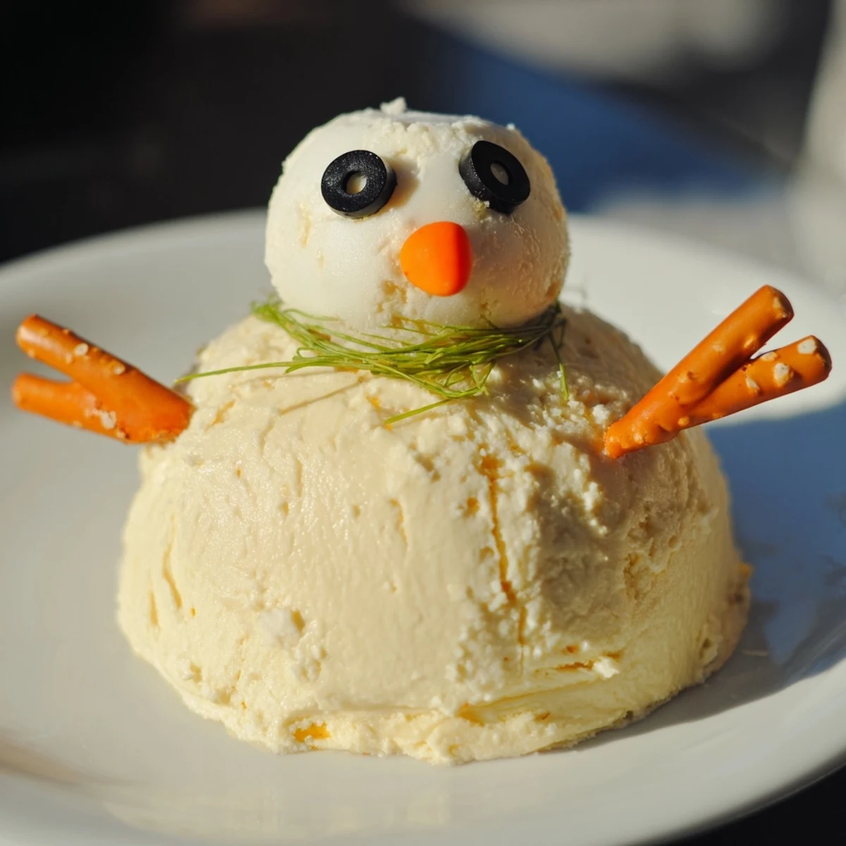 Melted Snowman Cheese Bites are festive, with creamy cheese snowmen, adorned with black olive eyes, carrots, and pretzels.