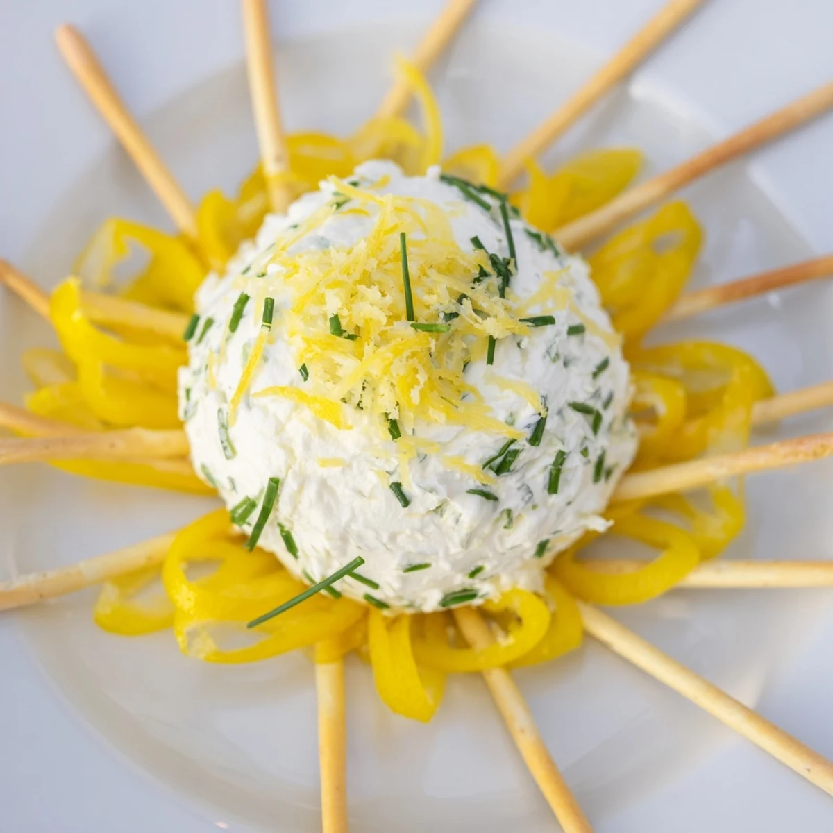 Vibrant Tuscan Sunburst appetizer: yellow bell peppers form sunburst rays, surrounding creamy, zesty goat cheese.