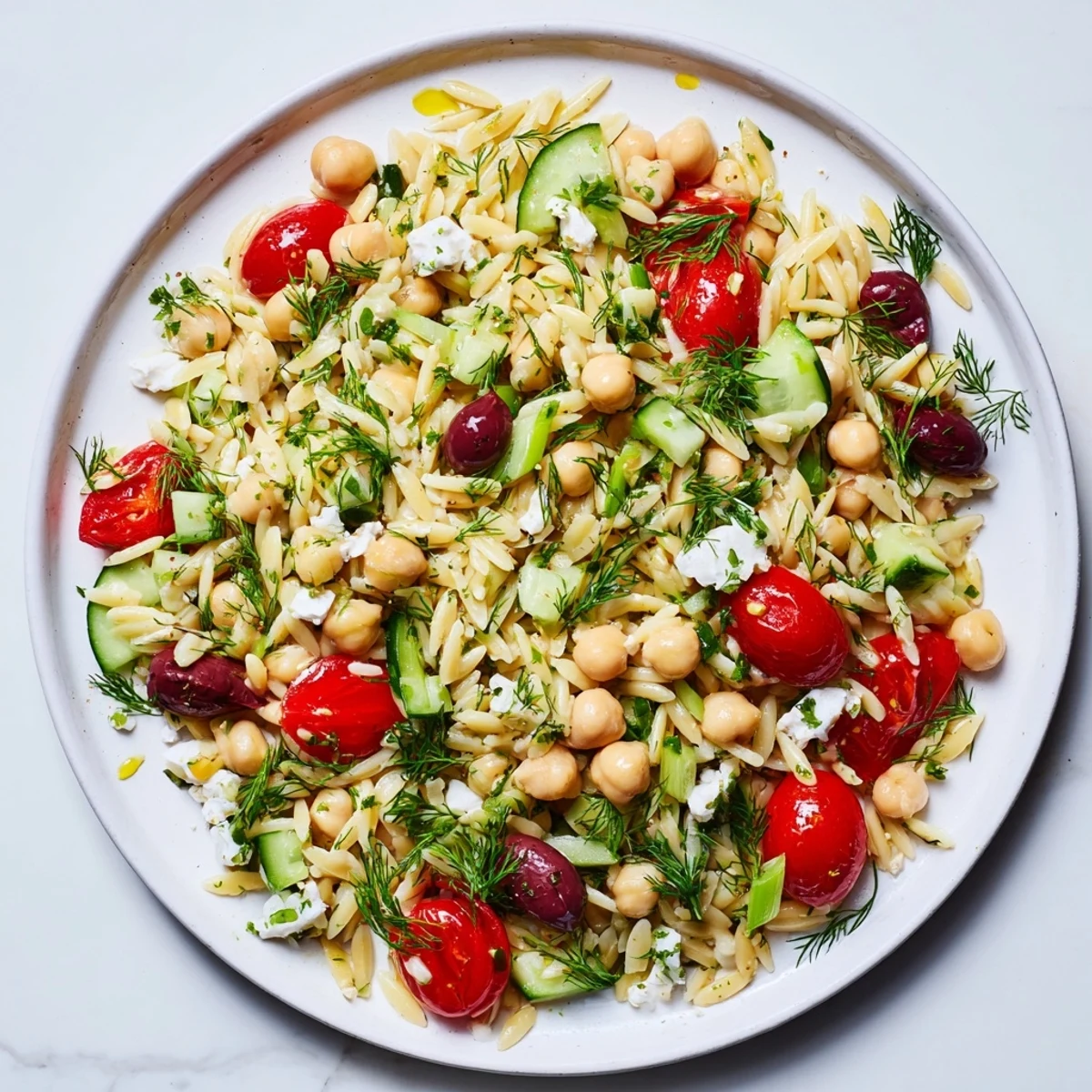 A close-up view of creamy Greek Lemon-Orzo Bean Salad, highlighting tender orzo and juicy tomatoes.