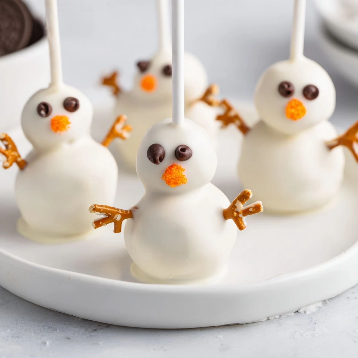 Sweet, adorable Oreo Snowman Cake Pops, showcasing a delicious dessert with pretzel arms.
