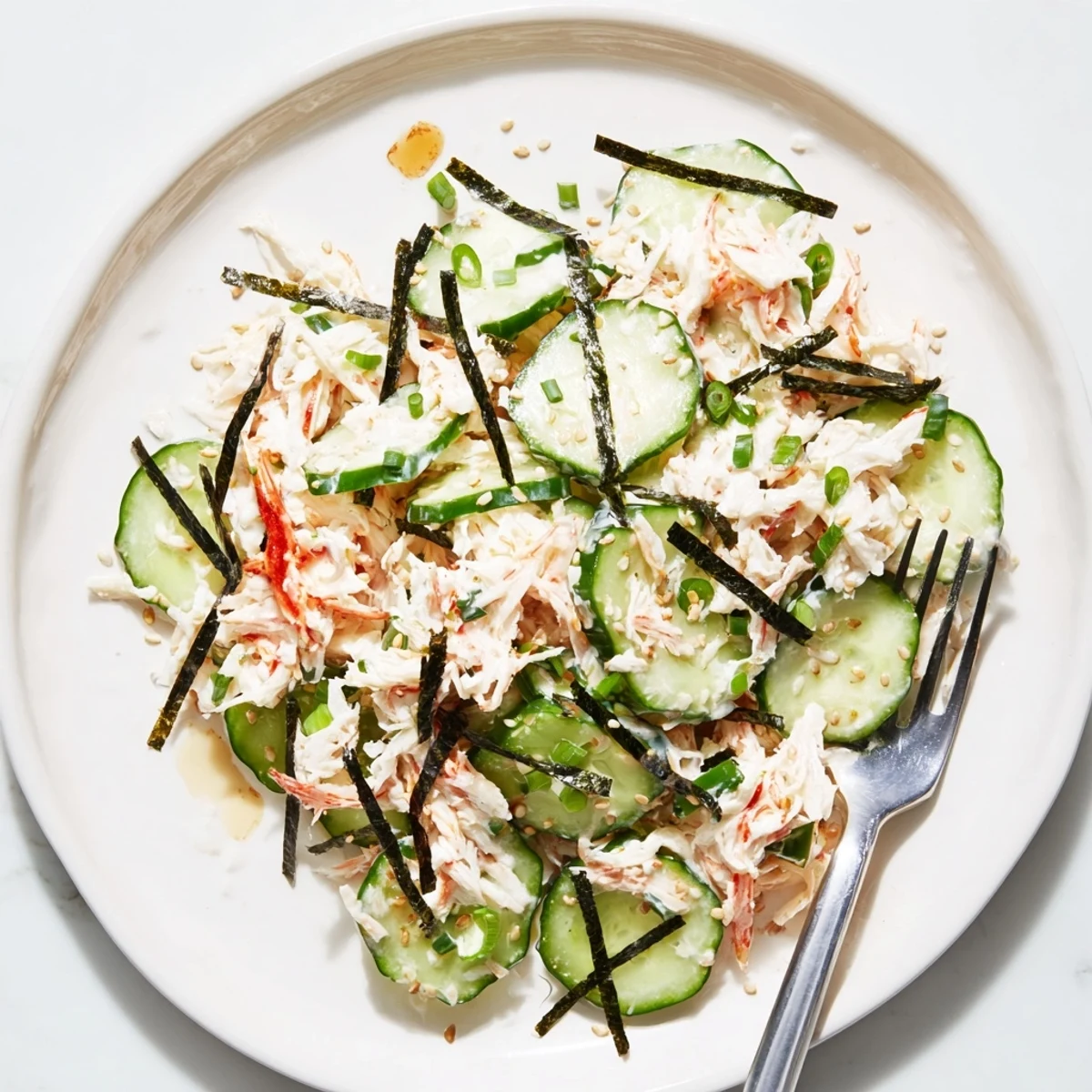Fresh California Roll Cucumber Salad served chilled with nori strips and pickled ginger on the side.