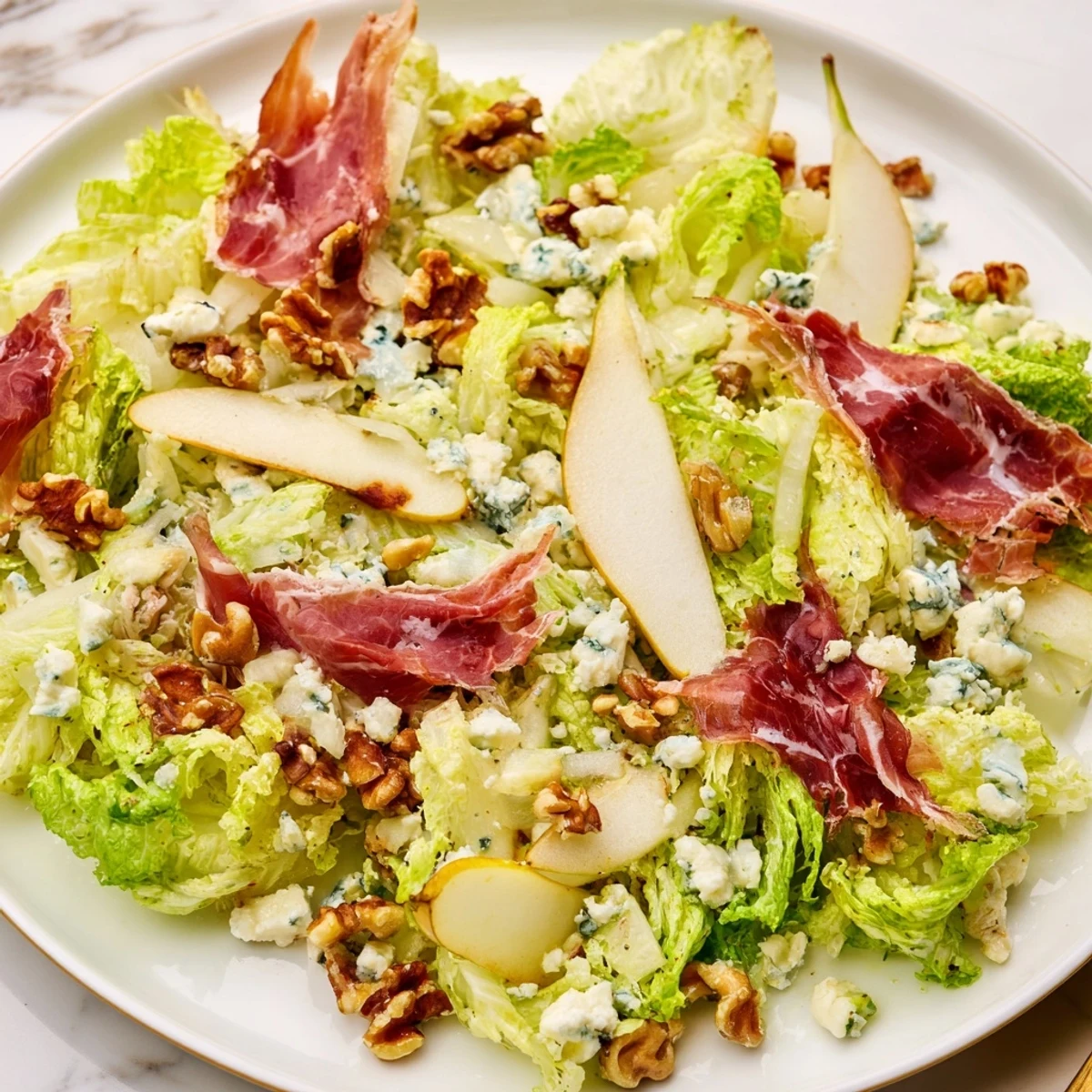 Enjoy Frisée, Pear, Blue Cheese, and Crispy Prosciutto Salad as a light lunch, featuring toasted walnuts and a tangy vinaigrette.