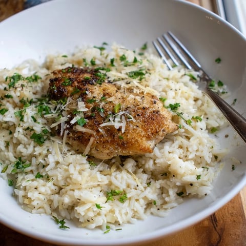 Creamy One-Pot Garlic Parmesan Chicken and Rice garnished with parsley and extra cheese.  