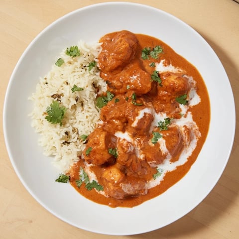 Image of creamy Butter Chicken served with fragrant rice pilaf, a comforting Indian dinner.