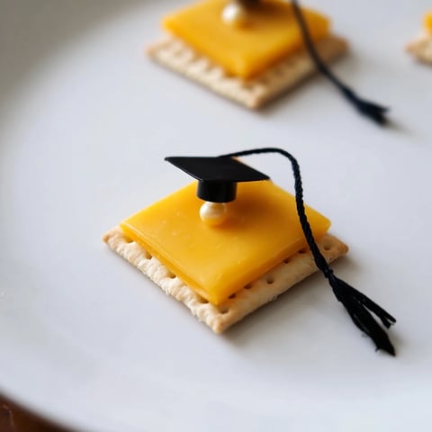 A platter of The Graduation Cap Snacks, cheesy squares with licorice tassels ready to eat.