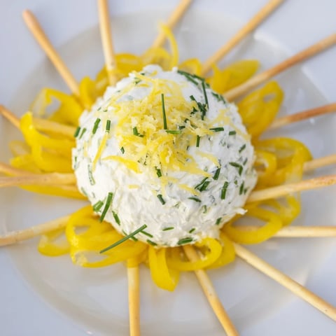 Vibrant Tuscan Sunburst appetizer: yellow bell peppers form sunburst rays, surrounding creamy, zesty goat cheese.