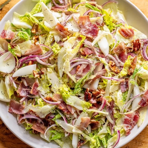A close-up of a Bitter Greens Salad with Warm Bacon Dressing, a savory, inviting meal.