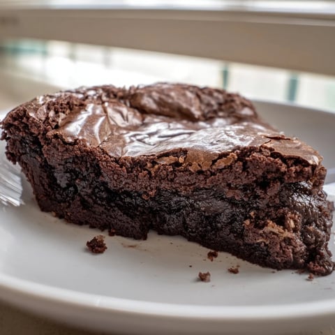 Warm Ina Garten Brownie Pudding with a crackly top, served with a scoop of vanilla ice cream.
