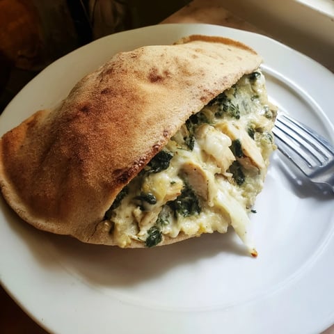 Golden-brown, toasted pita pockets stuffed with creamy spinach, artichoke, and tender chicken, served warm on a plate.  