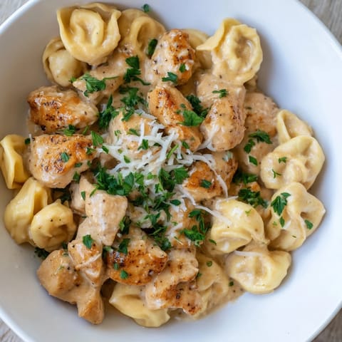 A steaming bowl of Zesty Cajun Garlic Parmesan Chicken Tortellini showcases hearty ingredients and cheesy goodness.