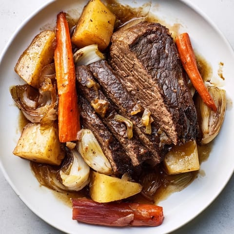 Sizzling close-up of Sunday Pot Roast, showcasing the fall-apart meat and vibrant roasted veggies.