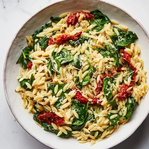 Spoonful of creamy Tuscan Orzo Bowl, featuring spinach and herbs, is a satisfying Italian meal.