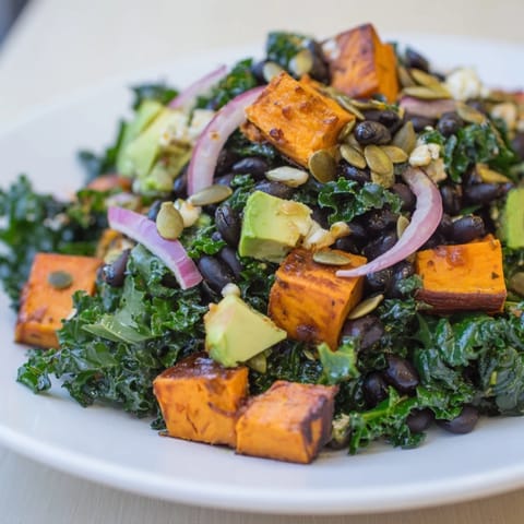 A close-up shot of a vibrant Massaged Kale Salad, showing fresh avocado and crunchy pumpkin seeds.