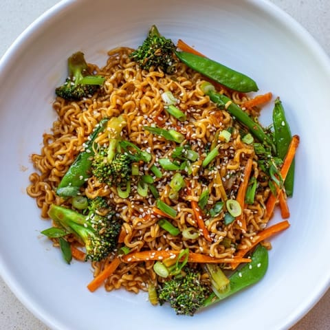 Savory Ramen Noodle Stir-Fry Remix, glistening with sesame oil and garnished with green onions and seeds.