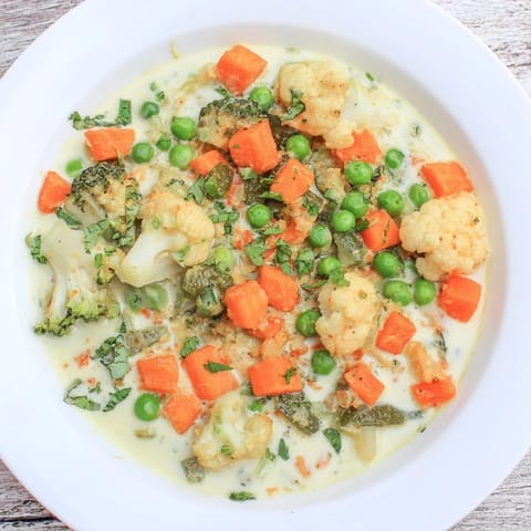 Golden Veggie Coconut Curry, garnished with cilantro, served in a bowl with fluffy rice.