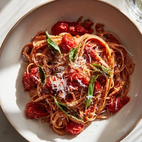 A close-up of the delicious Cozy Fireplace One-Pan Tomato Basil Pasta, bubbling in a Dutch oven with herbs.