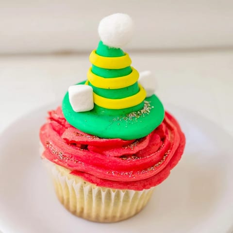 Festive Elf Hat Cupcakes displayed on a tower, starring whimsical red and green hat decorations, ready for a Christmas party.