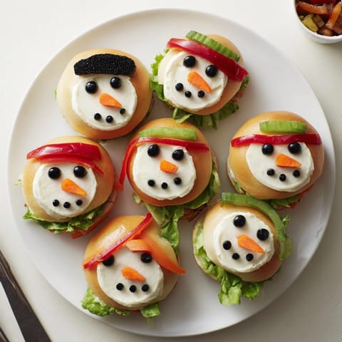 Festive snowman mini bagel sandwiches, decorated with olives and bell peppers, ready to eat.