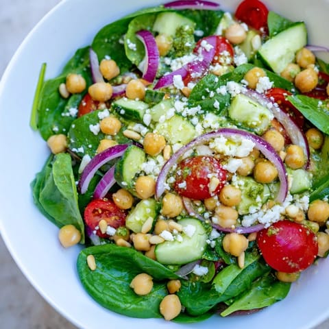 This Pesto Chickpea and Spinach Salad showcases colorful ingredients—chickpeas, spinach, and tomatoes—tossed in flavorful pesto.