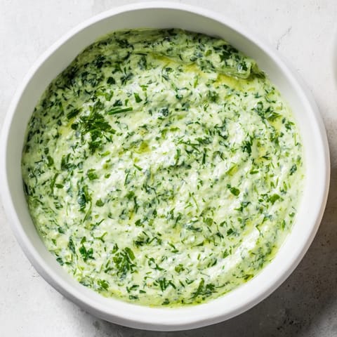 A close-up of fresh herbs blended into luscious Green Goddess Dip, showcasing its bright green color and texture.