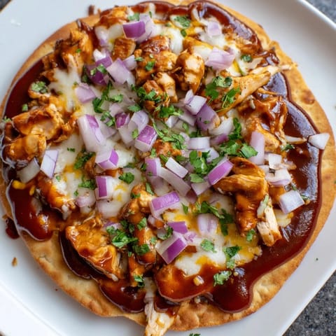 A close-up of smoky BBQ Chicken Flatbread with vibrant red onion, offering a delicious American meal.
