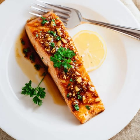 A close-up of sticky, caramelized Honey Garlic Glazed Salmon with a glossy buttery glaze and tender flaky interior.