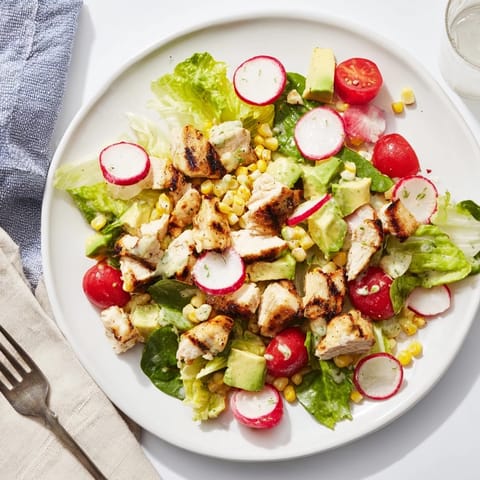Fresh Roasted Corn & Chicken Chopped Salad served over chopped romaine with juicy tomatoes, red onion, and a zesty cilantro garnish.  