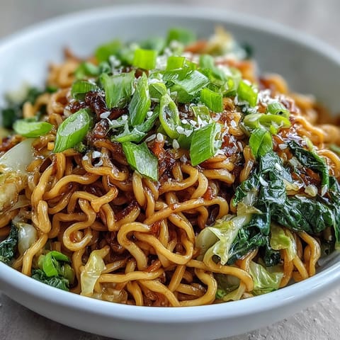 Steaming bowl of vegetarian Fried Cabbage Ramen stir-fry, featuring chewy noodles and crispy browned cabbage garnished with fresh scallions.