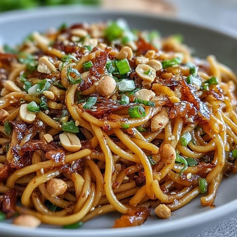 Vibrant Chili Crisp Noodles with garlic, scallions, and chili oil, served in a white bowl with chopsticks.  