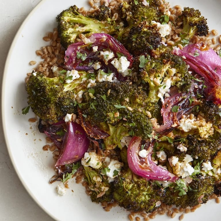 A warm bowl of farro topped with colorful roasted broccoli and red onion, ready to eat this meal.