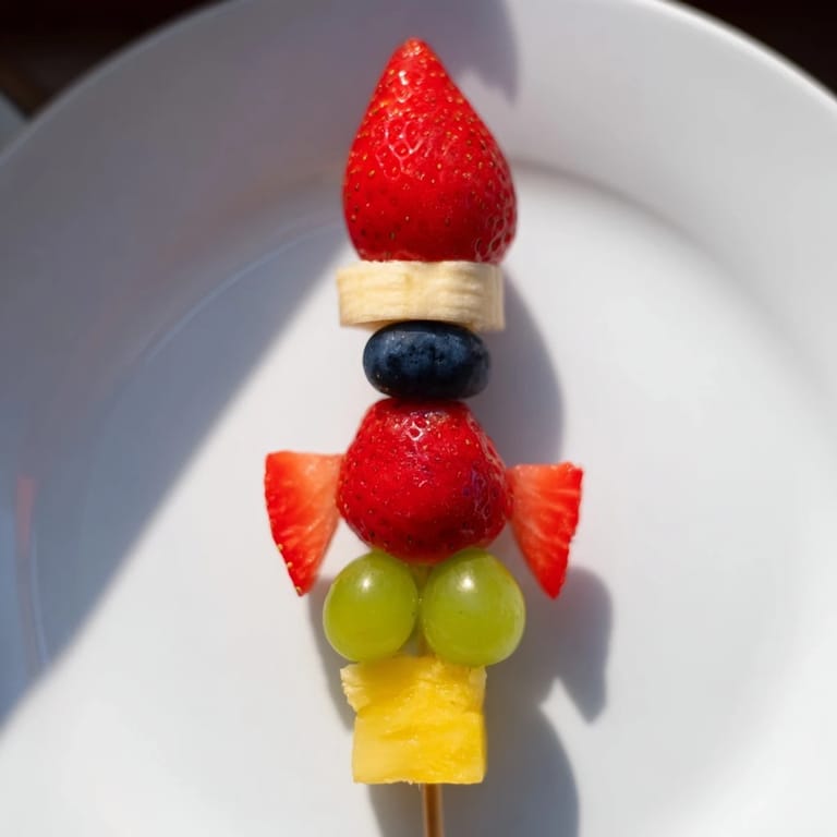Cool, colorful Rocket Ship Fruit Skewers ready to eat, with banana and berry details arranged.