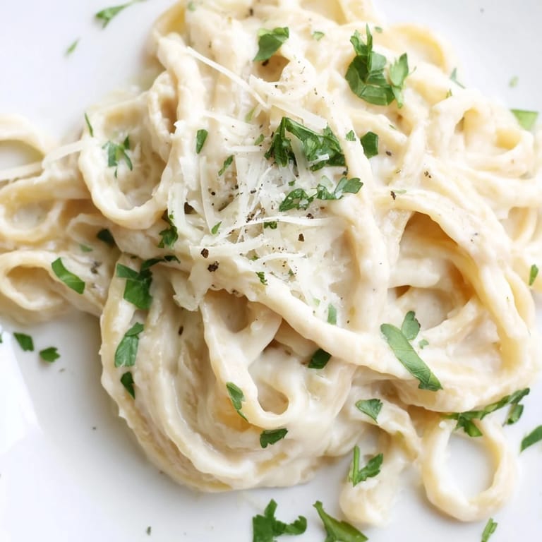 Serve Roasted Cauliflower Alfredo steaming in a bowl, finished with fresh parsley and extra Parmesan cheese.