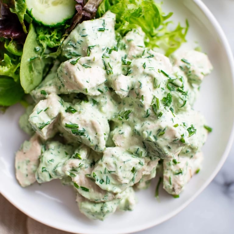 Tender herb-infused chicken salad with creamy Green Goddess dressing, nestled on a bed of greens and topped with bright cherry tomatoes.